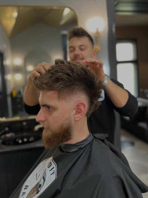 Barber la lucru cu un client în scaun